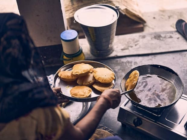 A woman in ghoonghat cooking Pooris
